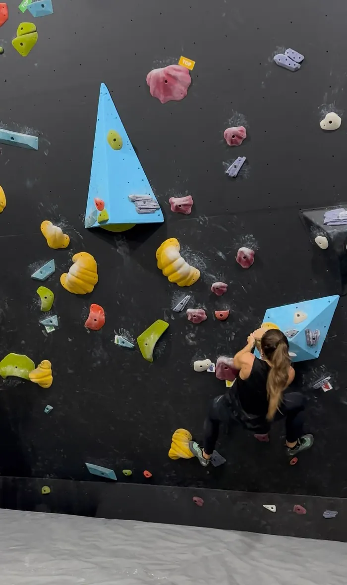 Paola escalando uma parede de boulder